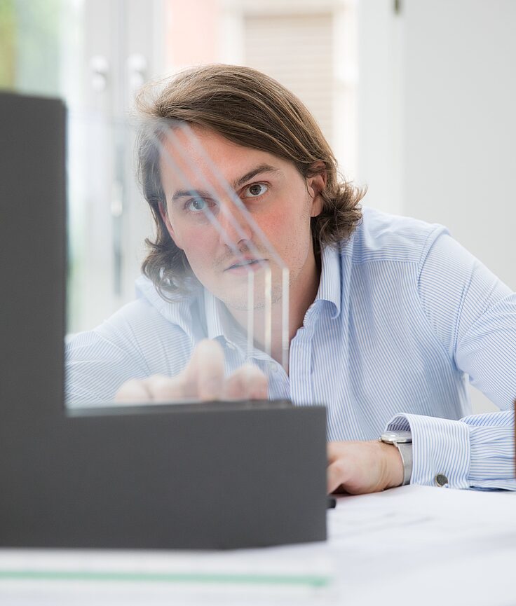 Man using a holographic display on a desk in a light-filled office.